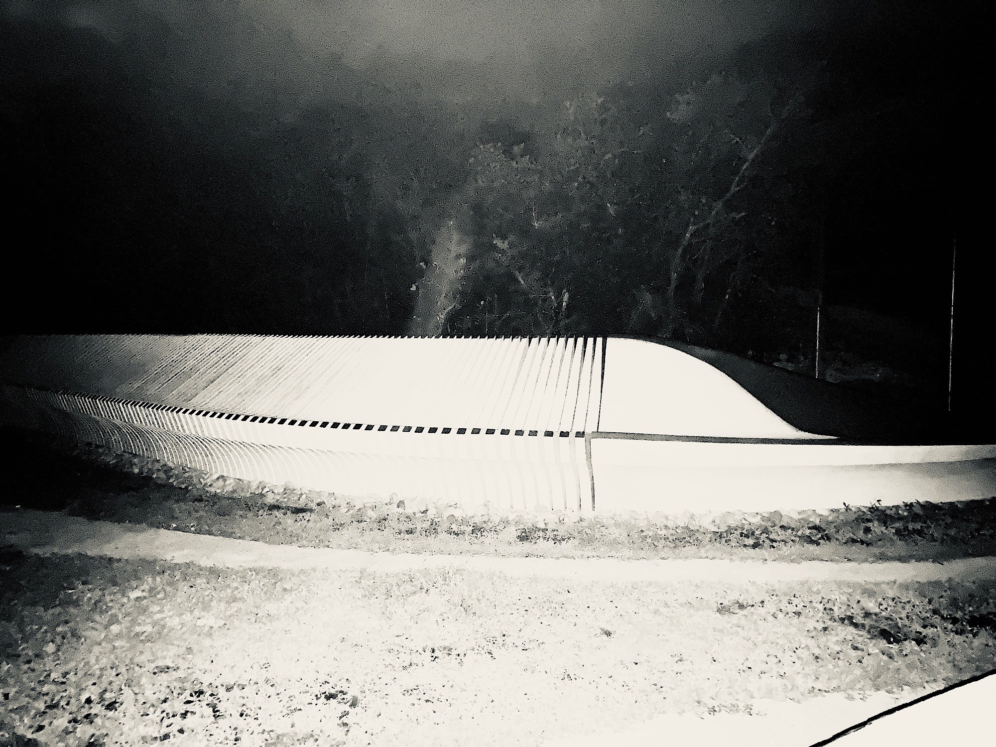 A pale curved form crossing ridged lines above a field of deep shadow.