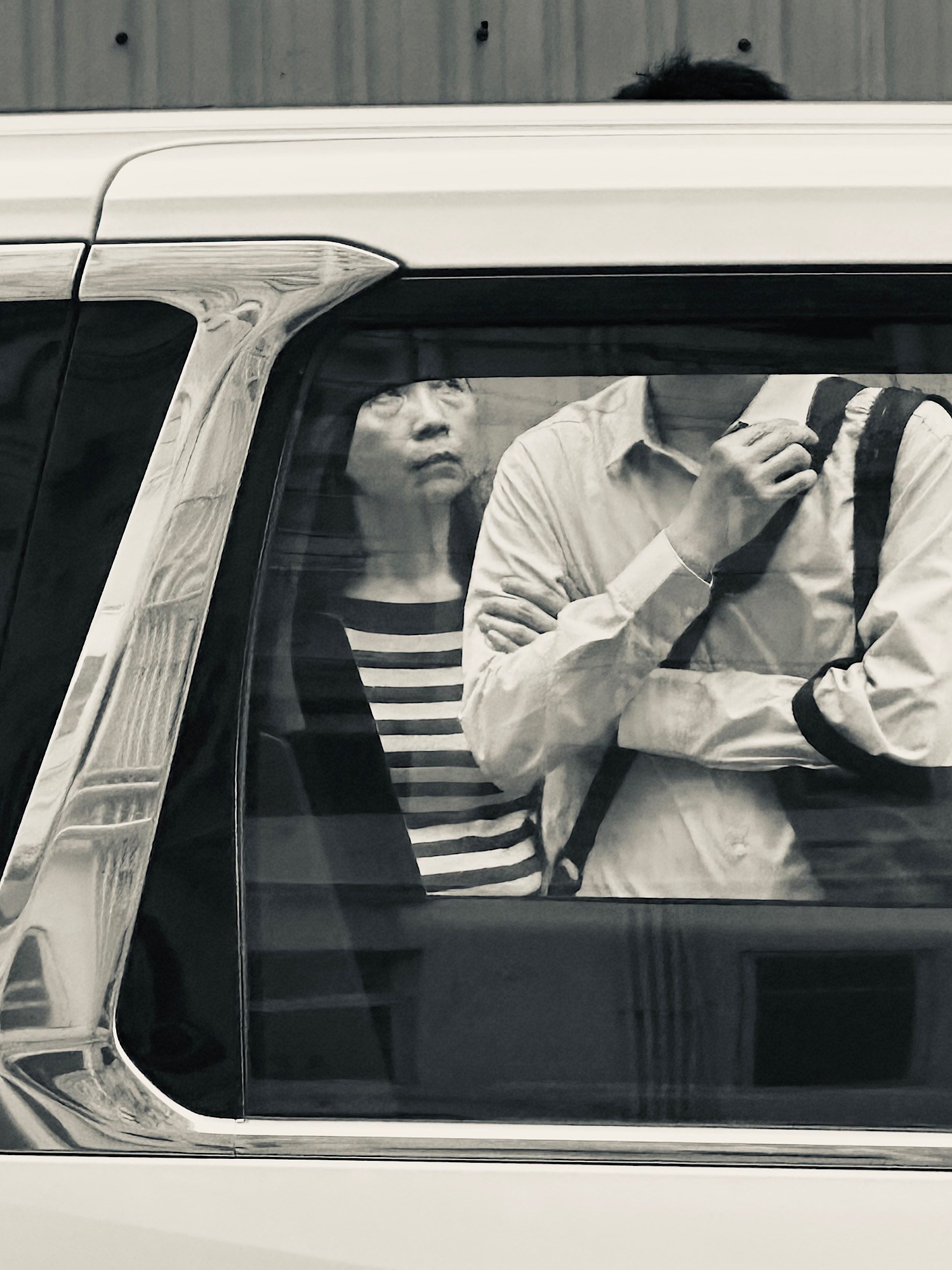 A passenger seen through the close frame of a vehicle window.