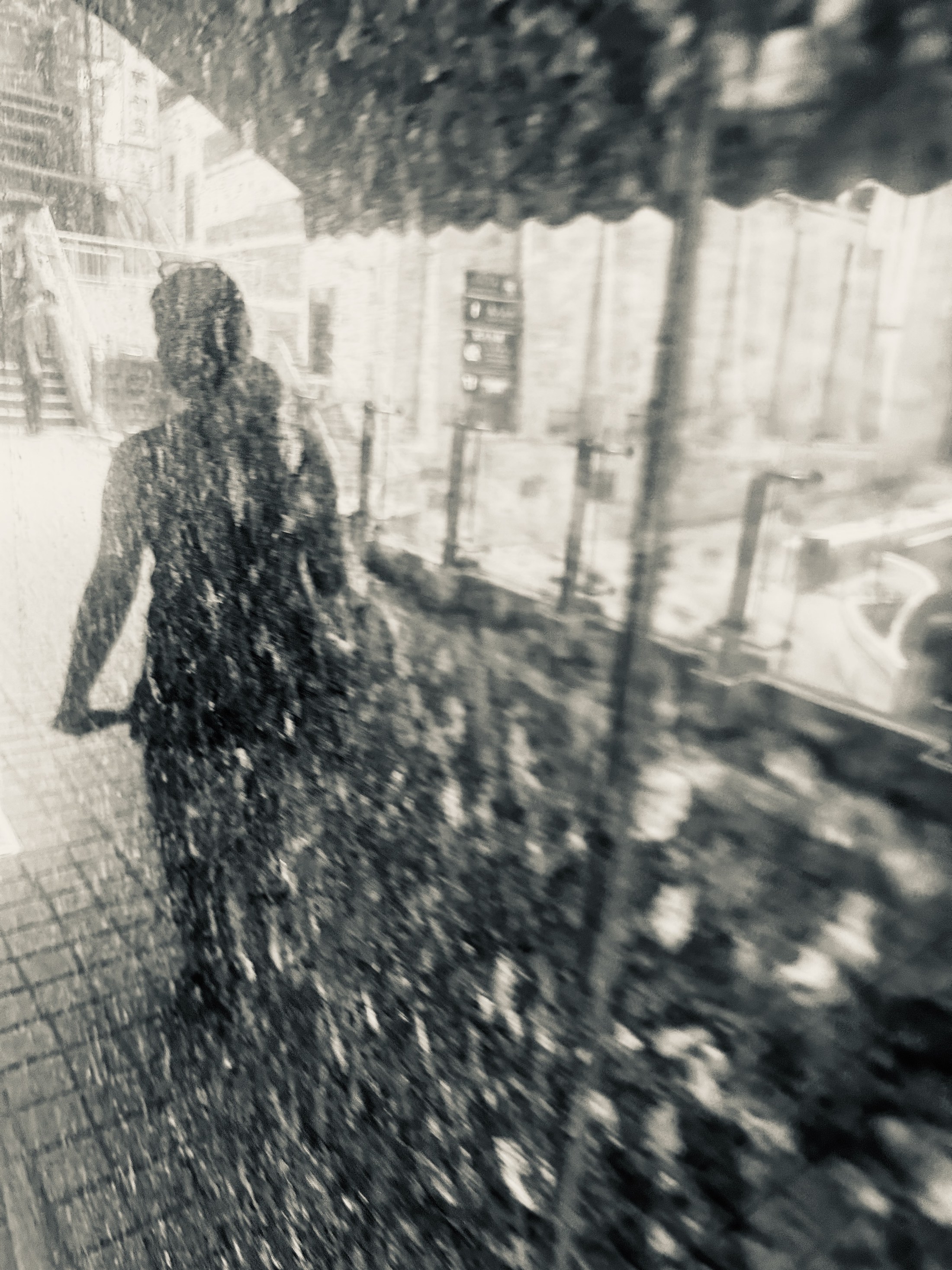 A dark pedestrian silhouette passing behind a rain-covered window.