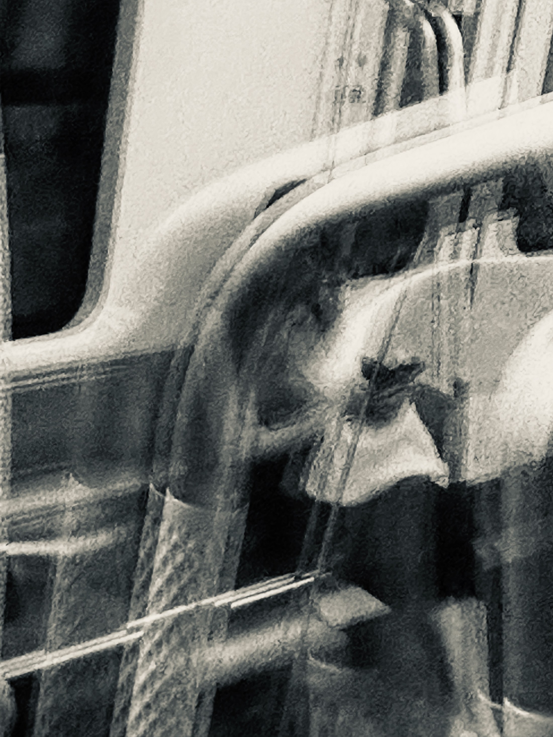 A passing figure fragmented across reflections on the side of a vehicle.