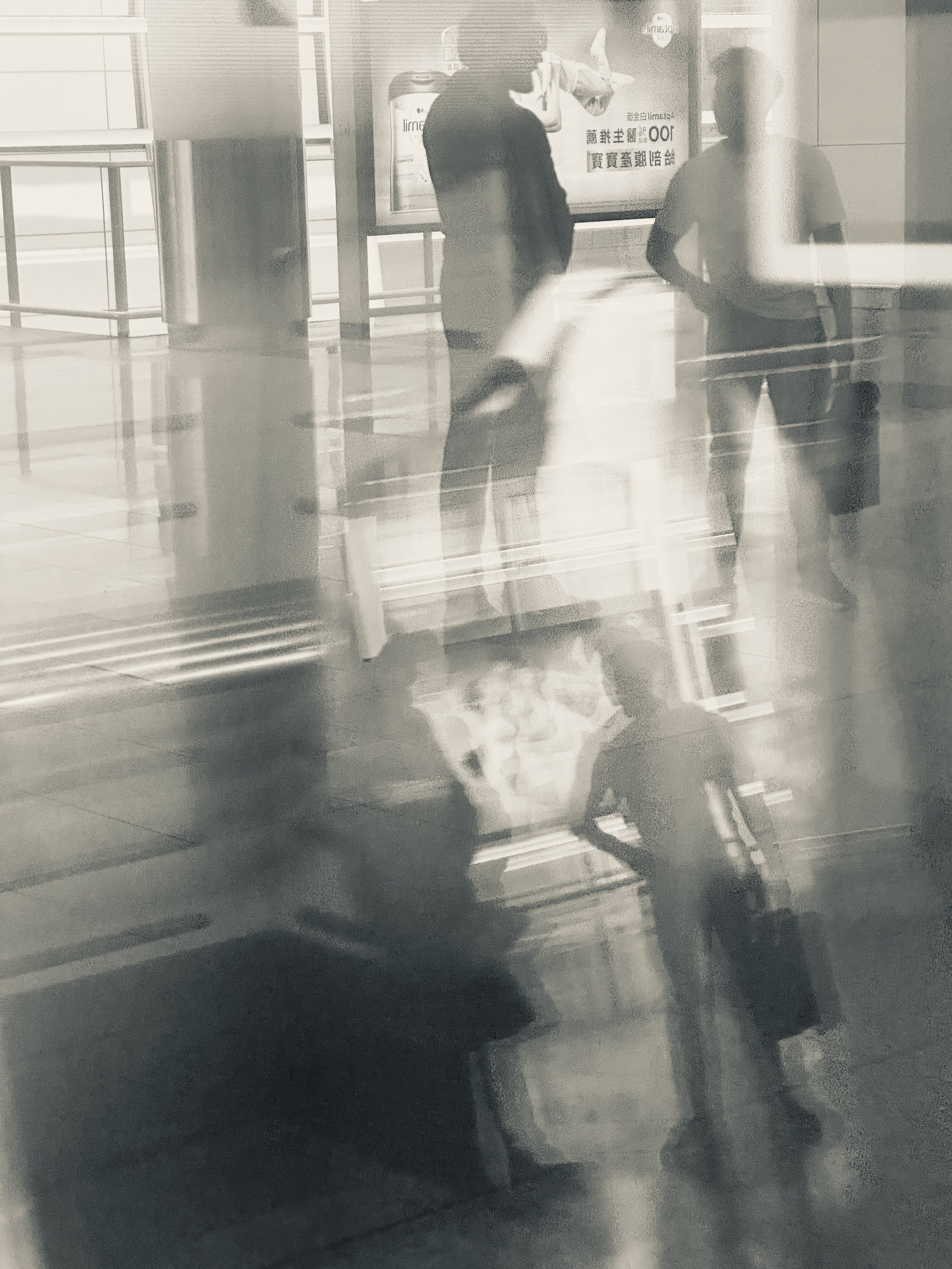 Figures in a pale concourse layered with door frames and reflections.