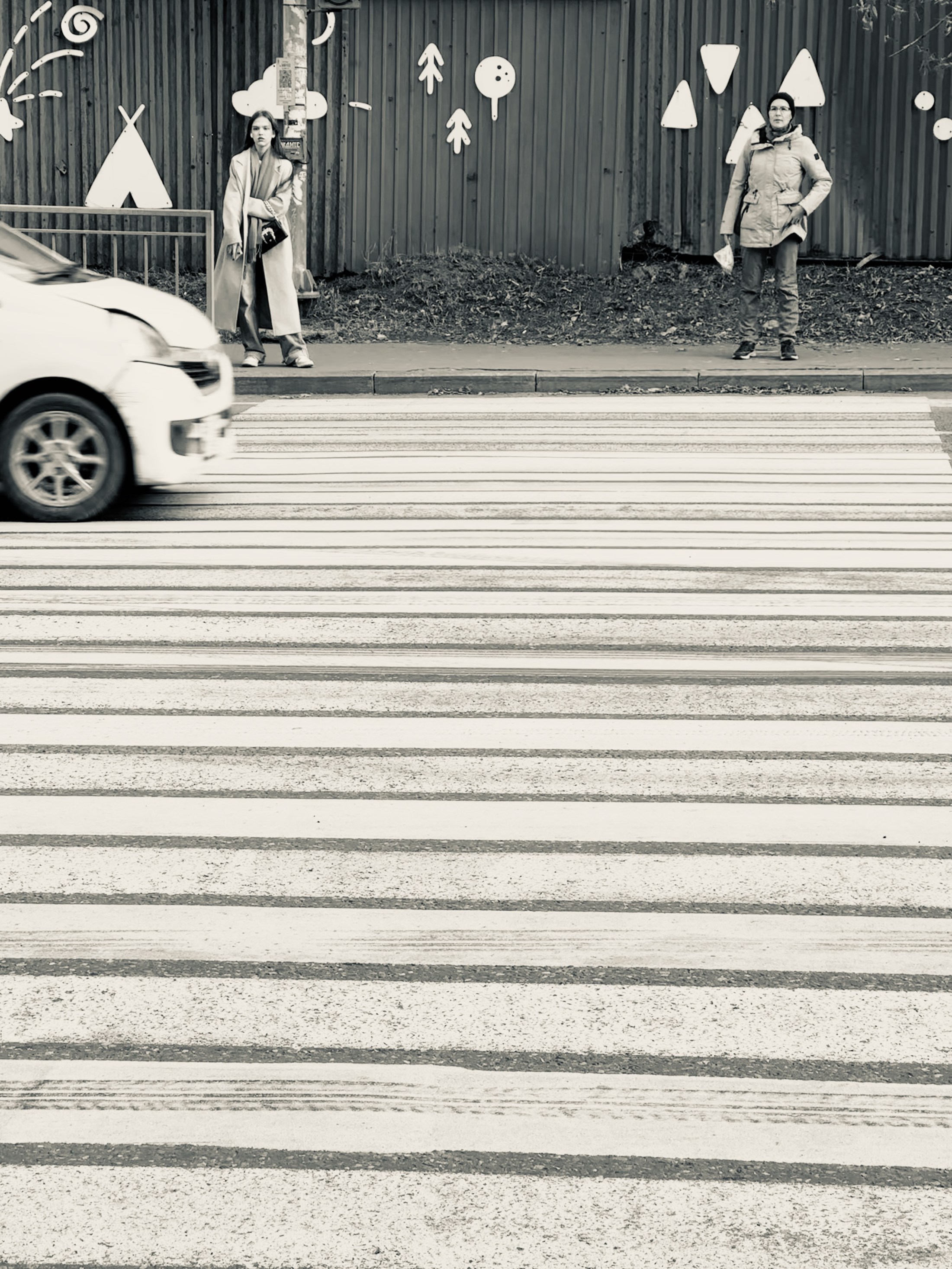 Pedestrians spaced across a striped zebra crossing in a high-contrast street scene.