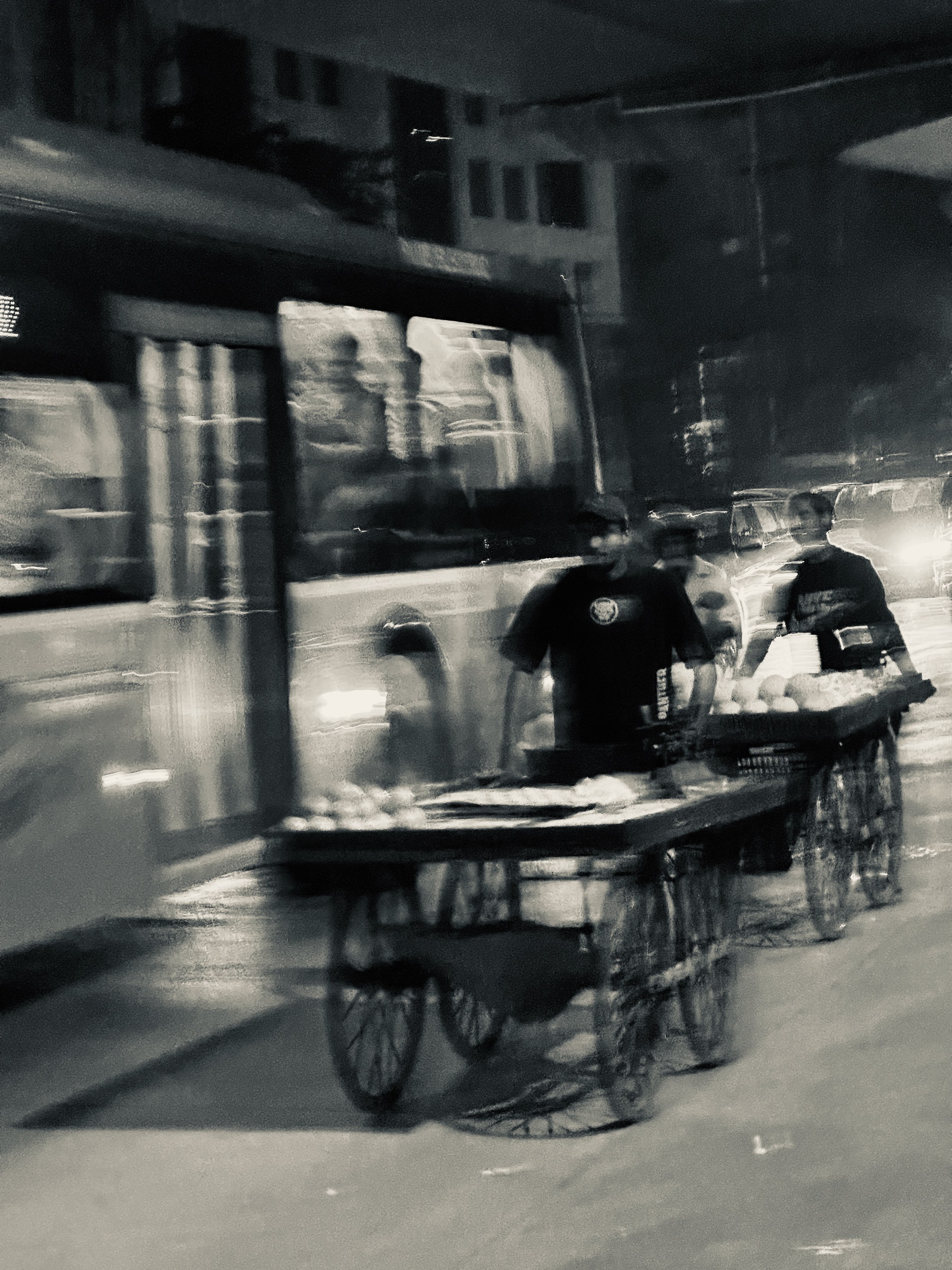 A person pushing a loaded handcart crosses the street in motion blur.