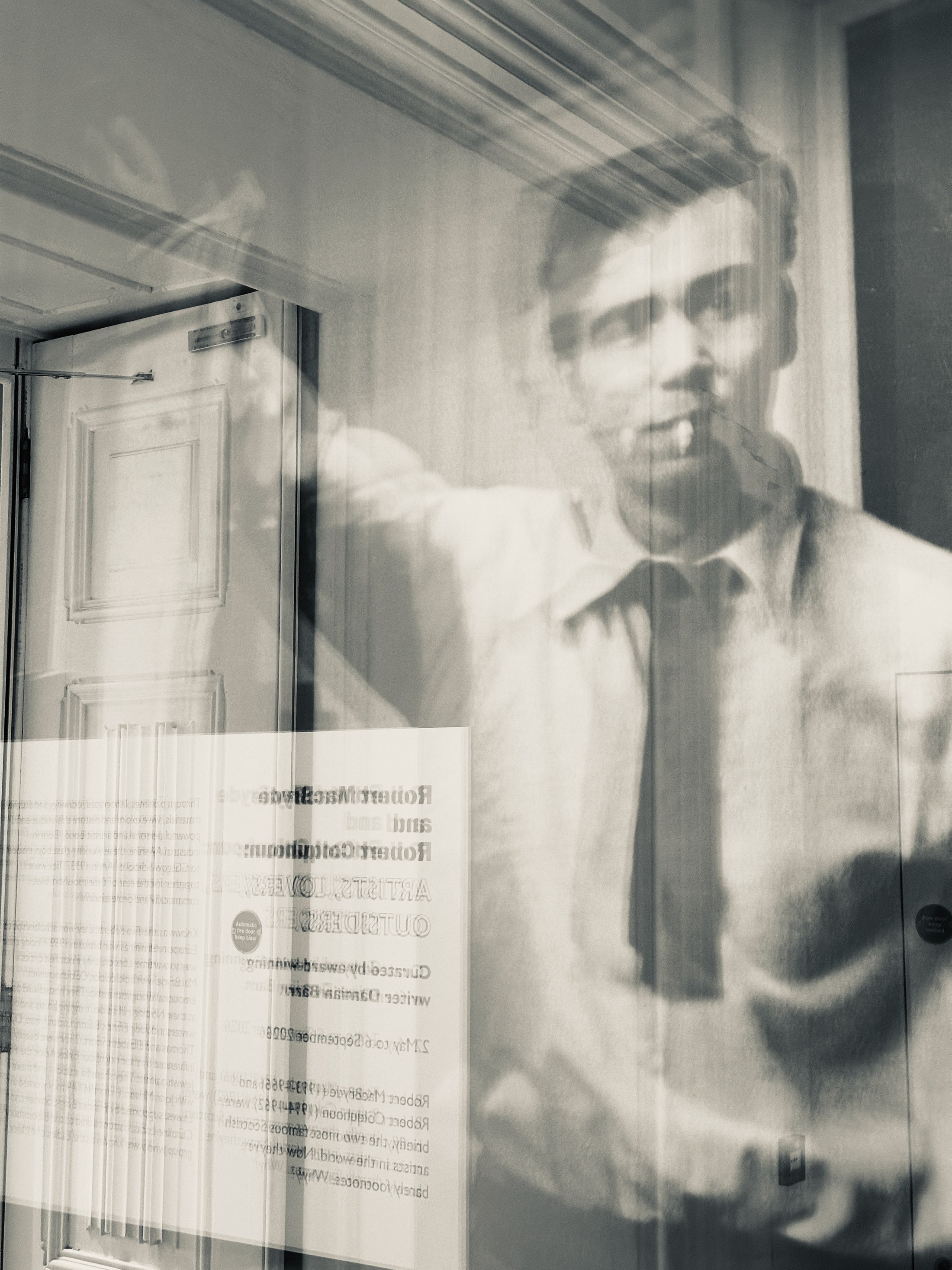 A human figure behind glass, layered with doorway lines and reversed lettering.